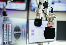 Media Broadcast startet DAB+ Plattform für NRW-Lokalradios Studiomikrofon in einem Rundfunkstudio, Mischpult und Computer im verschwommenen Hintergrund