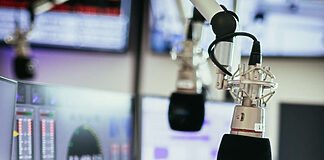 Media Broadcast startet DAB+ Plattform für NRW-Lokalradios Studiomikrofon in einem Rundfunkstudio, Mischpult und Computer im verschwommenen Hintergrund