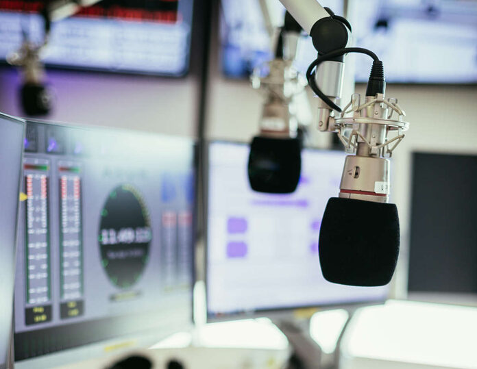Radio broadcasting studio: Microphone in the foreground, modern Studiomikrofon in einem Rundfunkstudio, Mischpult und Computer im verschwommenen Hintergrund